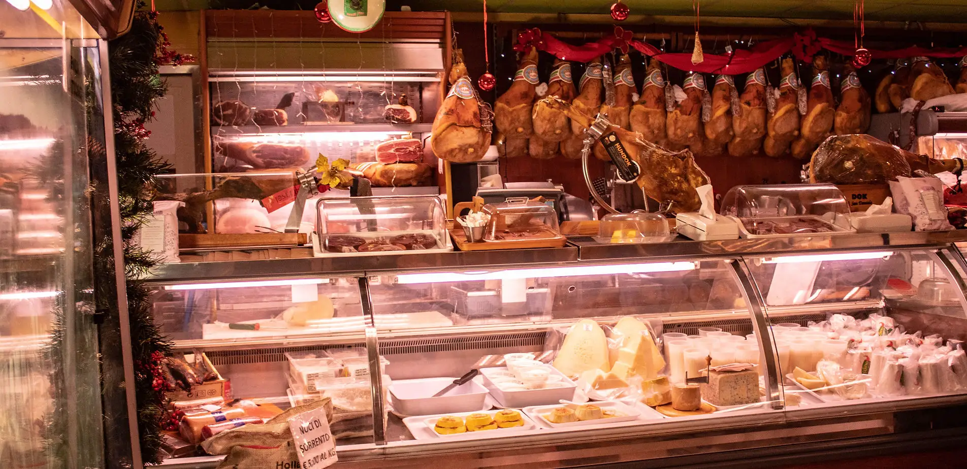 Il banco del negozio di Nola: prosciutti appesi, la vetrina dei formaggi e dei salumi