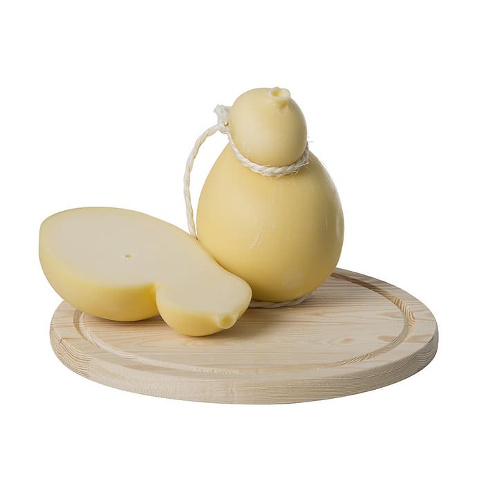 Un caciocavallo semi-stagionato intero accanto a uno spicchio, su un tagliere