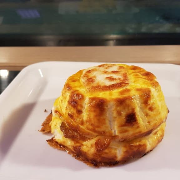 Una ricotta al forno dorata, nella forma a corona, su un piatto bianco