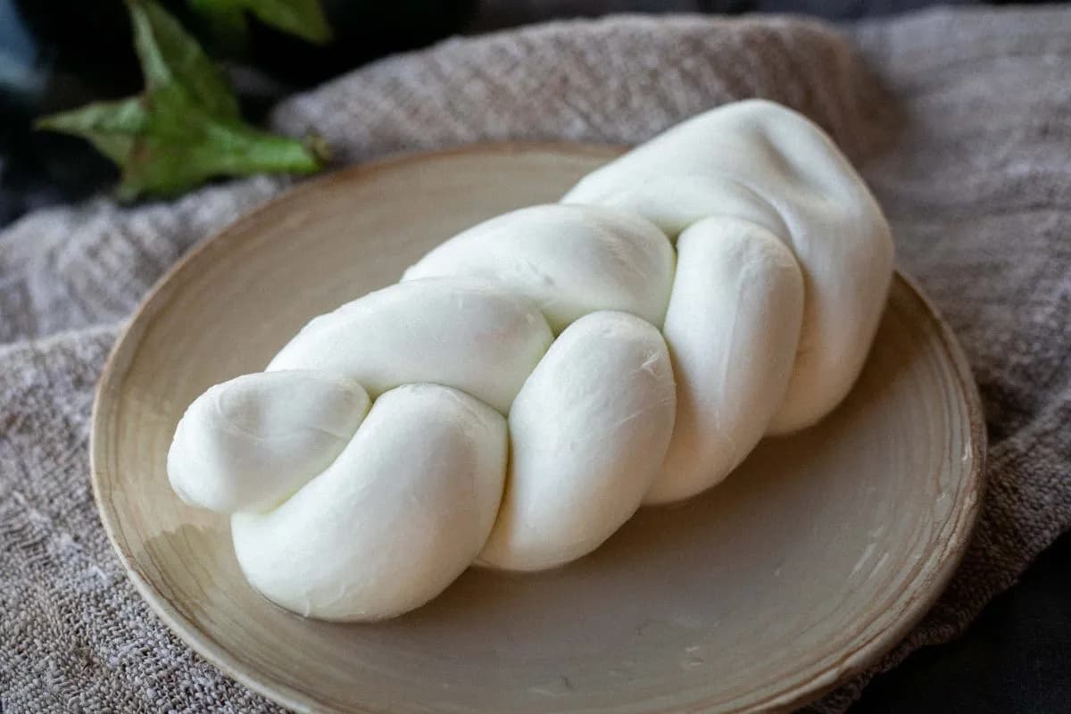 Una treccia di mozzarella di bufala su un piatto di ceramica chiara